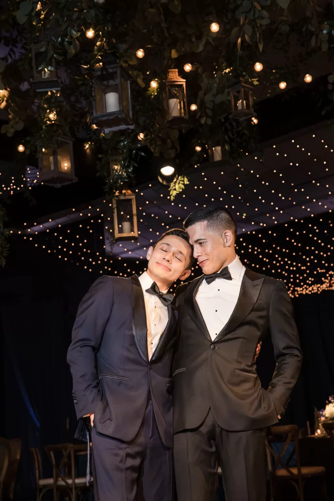 Alex and Jacob from Thater Made Events in navy and black tuxedos in dark ballroom at the hotel Del Coronado